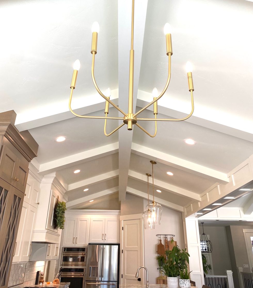 Vaulted white kitchen ceiling with a brass chandelier and pendant lights