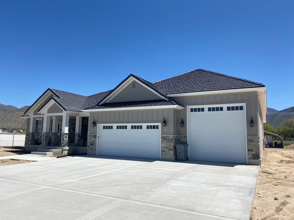 Single-story custom home with a three-car garage under a clear blue sky