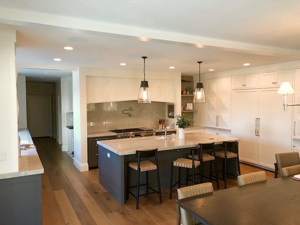 Kitchen with a dark island, white perimeter cabinets, and glass pendants, Park City